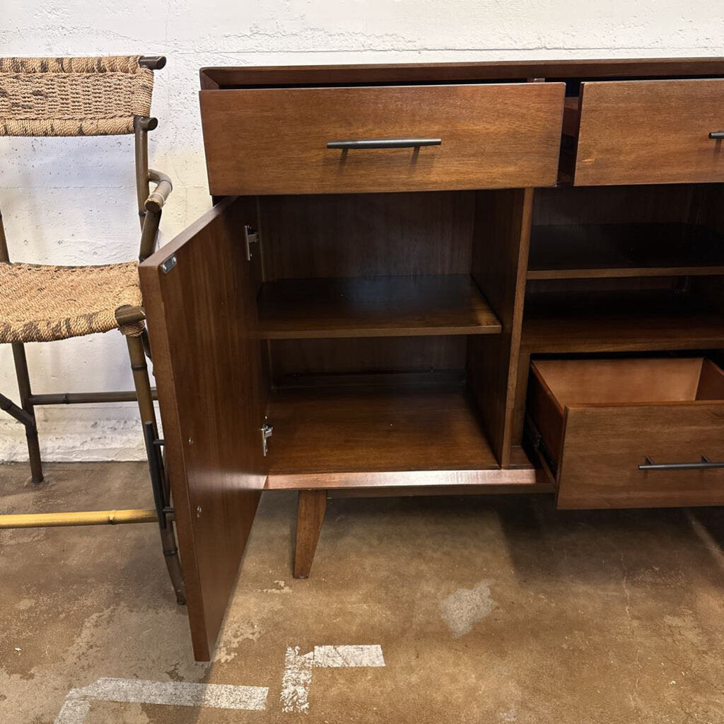 Wooden sideboard with open cabinet door and drawers on a concrete floor.