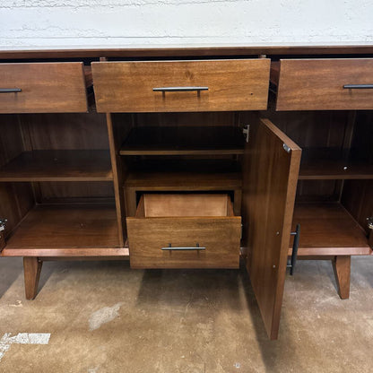 Wooden sideboard with open drawer on a concrete floor