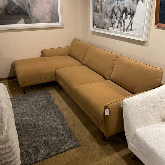 Brown sectional sofa in a room with framed pictures on the wall.