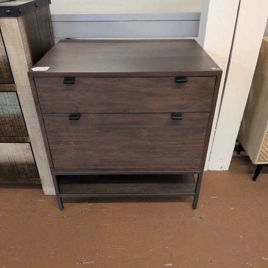 Wooden dresser with three drawers on a brown floor.