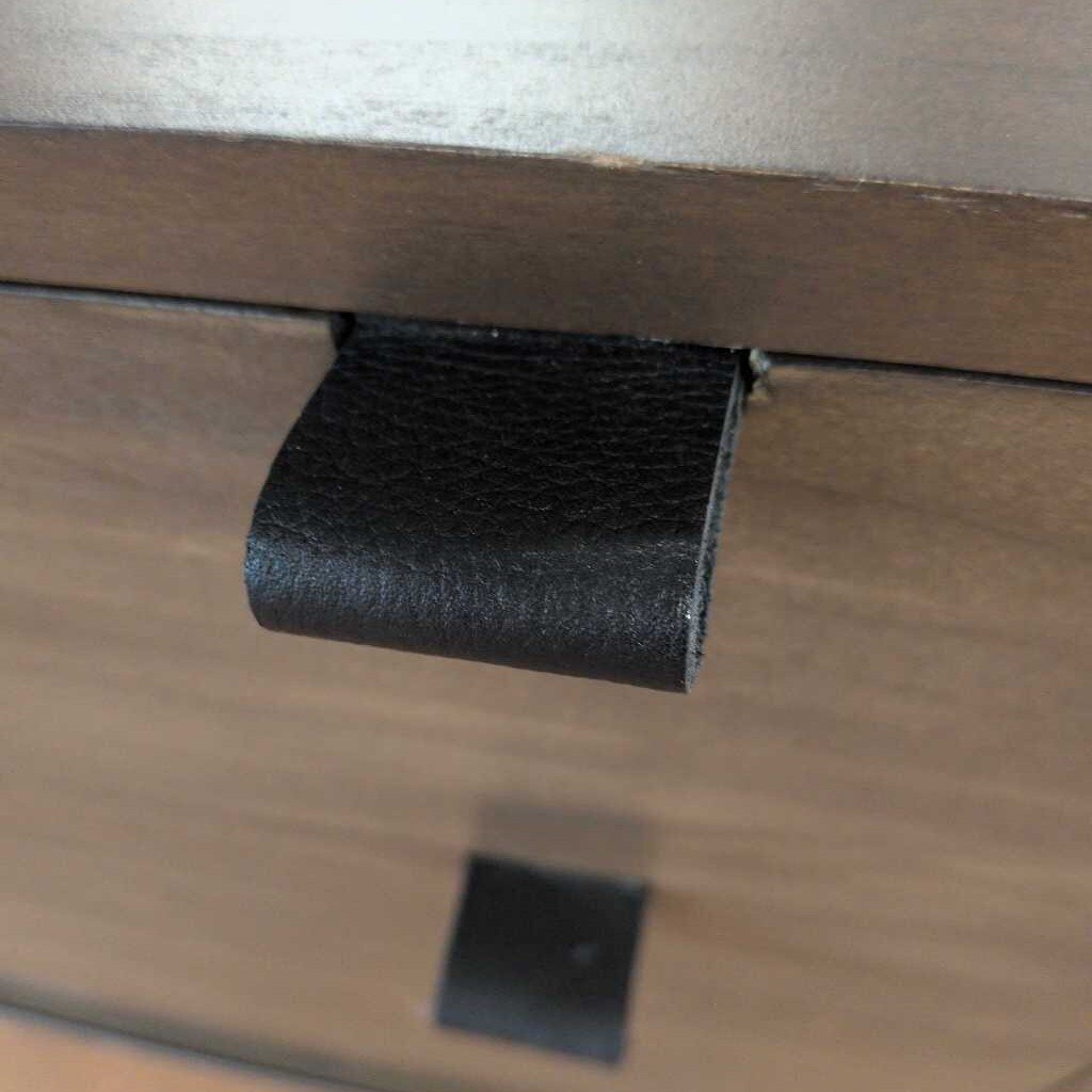 Close-up of a black leather handle on a wooden surface