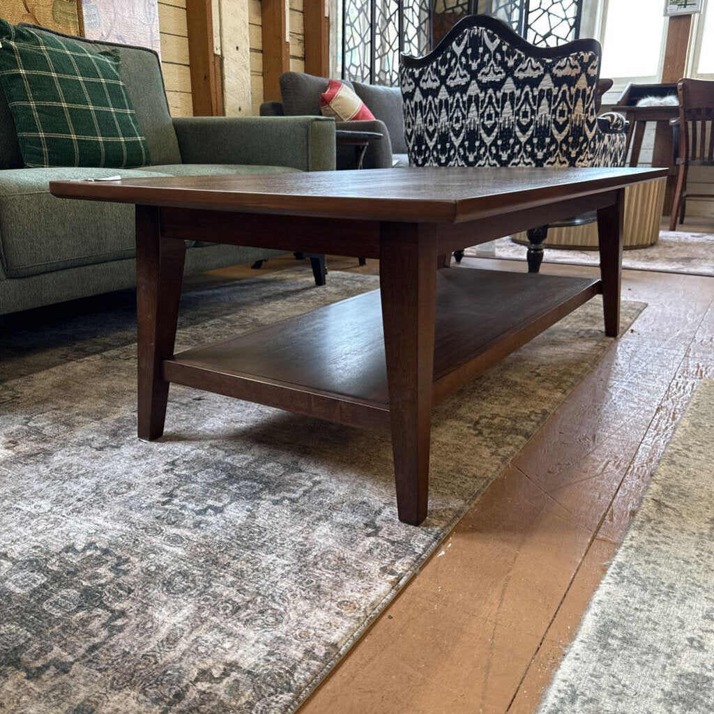 Wooden coffee table in a living room setting with a sofa and decorative pillows.