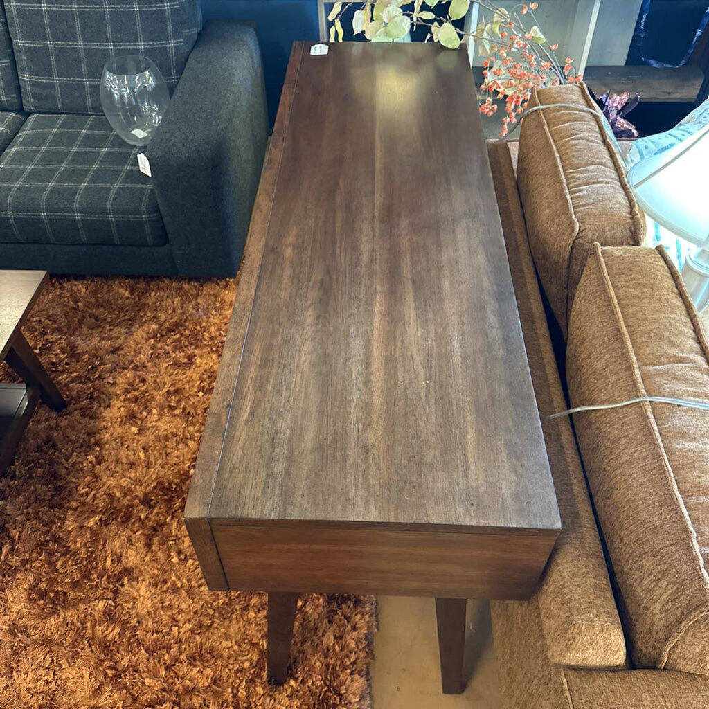 Wooden coffee table in a living room setting with a couch and rug.