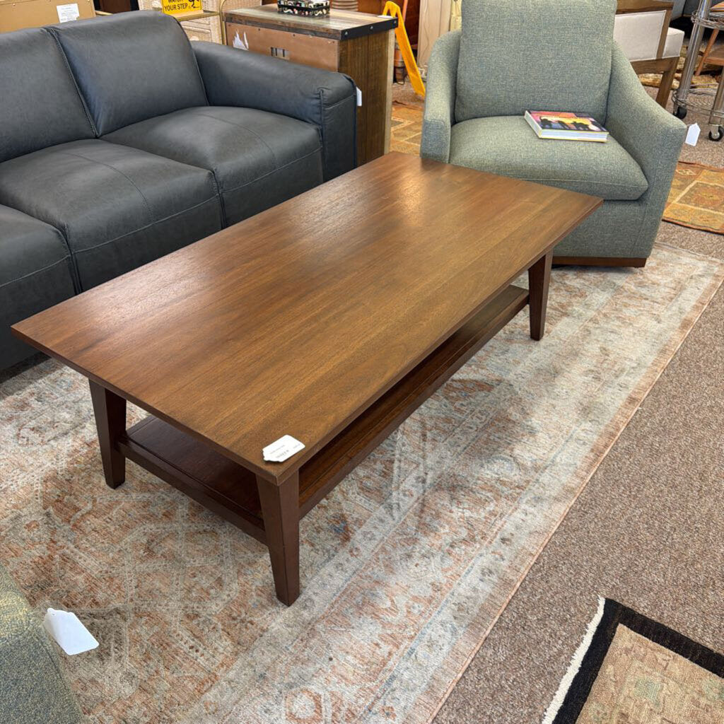 Wooden coffee table in a living room setting with a gray sofa and green armchair.