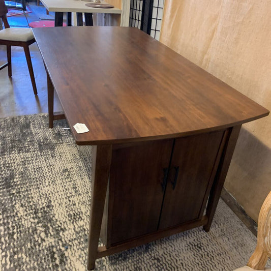 Wooden table with a cabinet underneath on a textured floor.