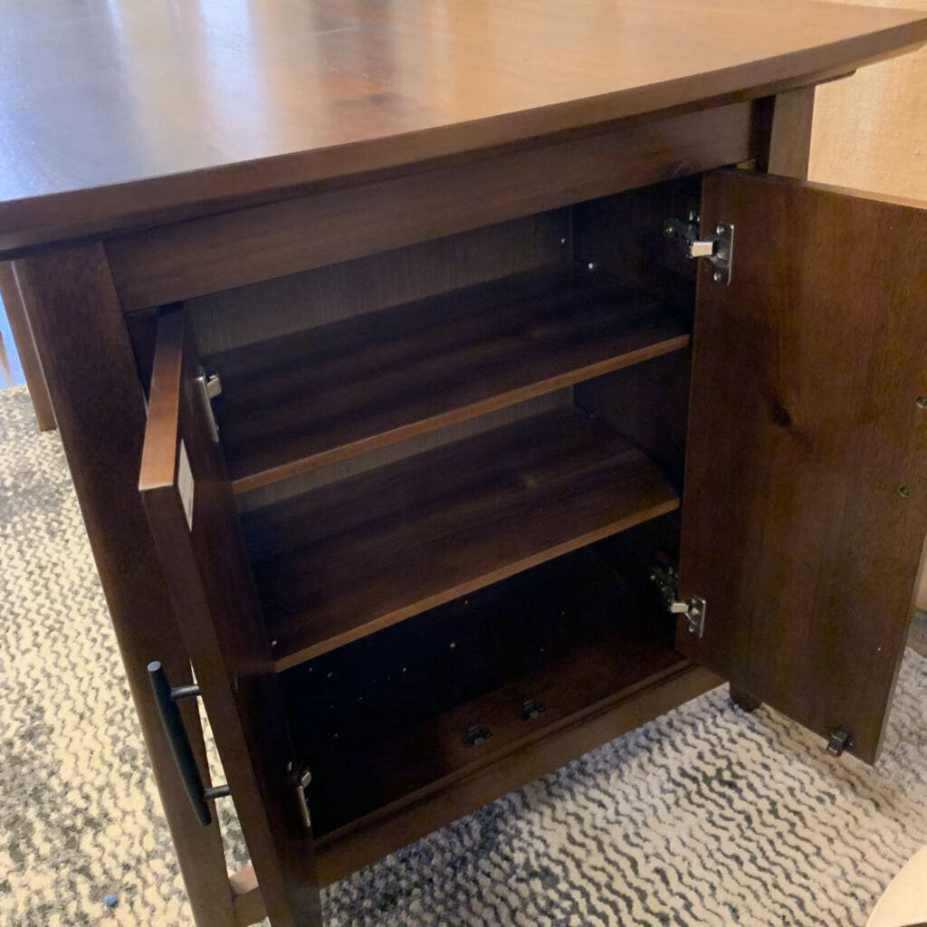 Wooden cabinet with open door revealing shelves on a textured floor.