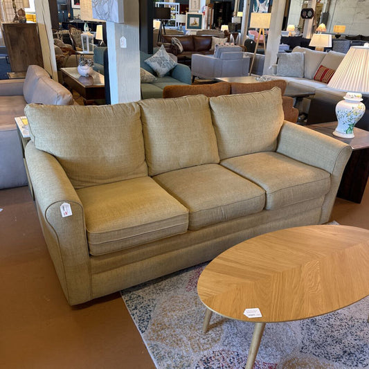 Beige sofa in a furniture store with a wooden coffee table.