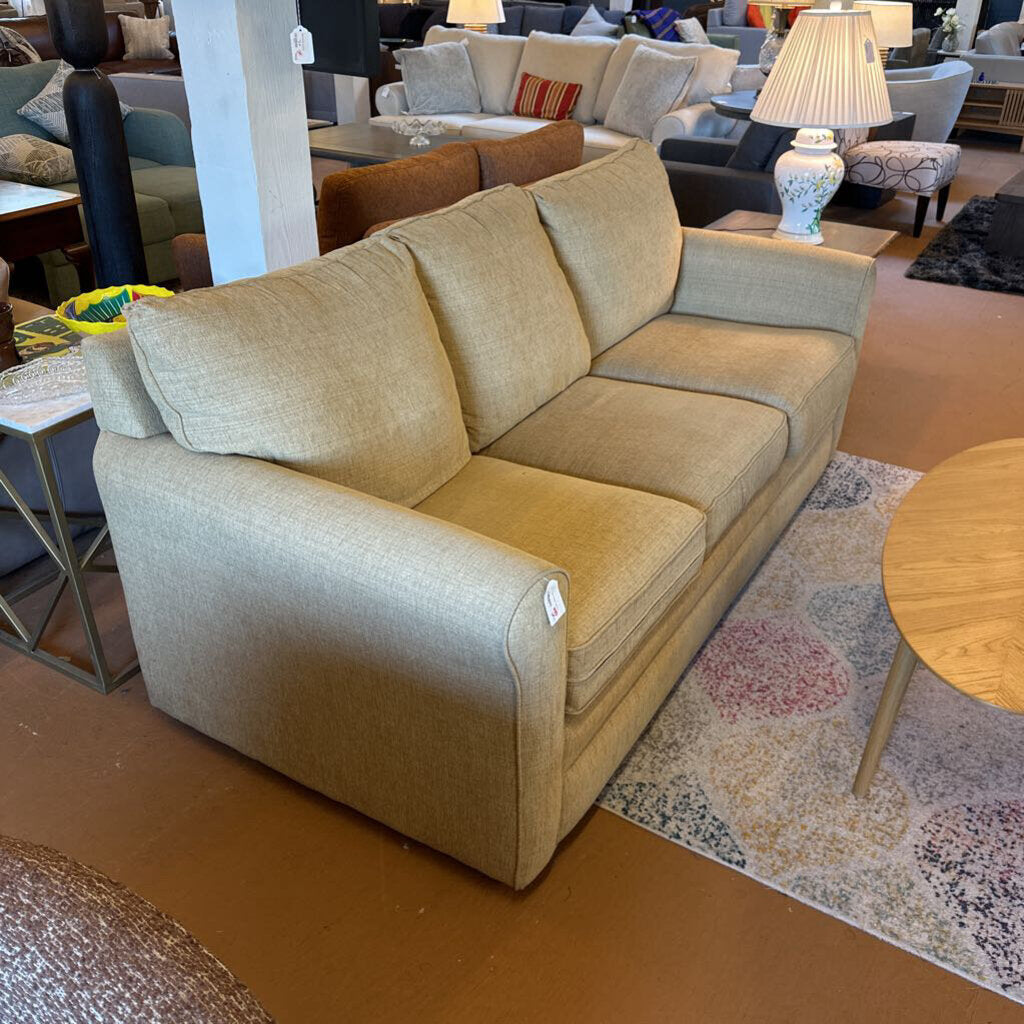 Beige sectional sofa in a showroom setting with other furniture.