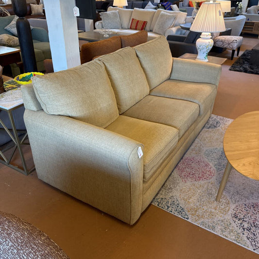 Beige sectional sofa in a showroom setting with other furniture.