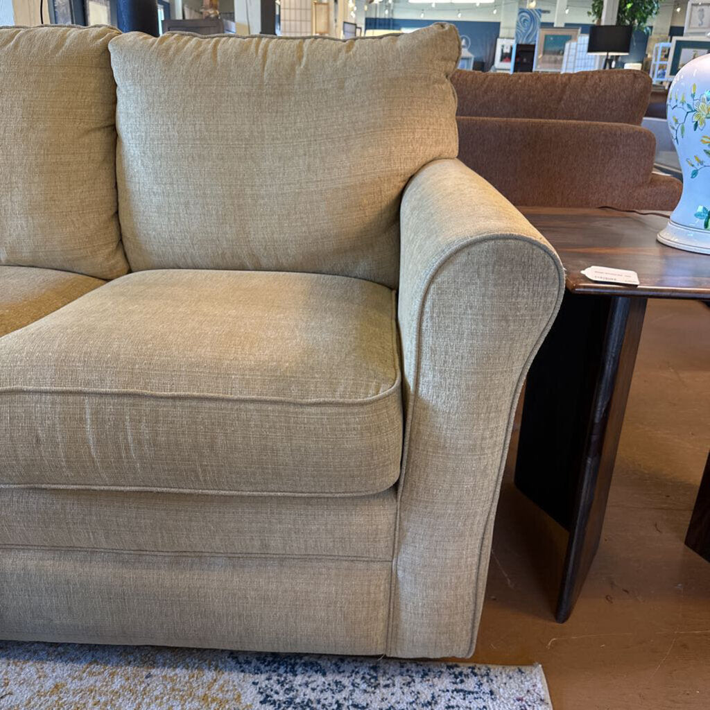 Beige sofa in a room with a wooden table and decorative items.