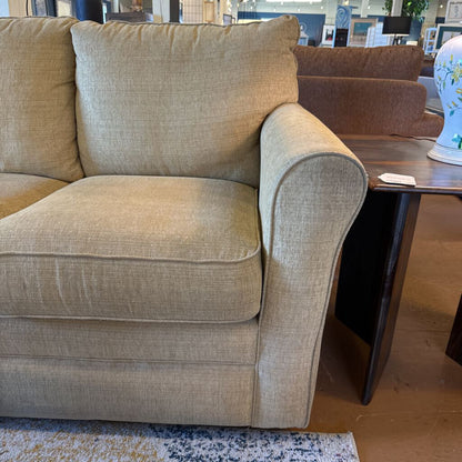 Beige sofa in a room with a wooden table and decorative items.