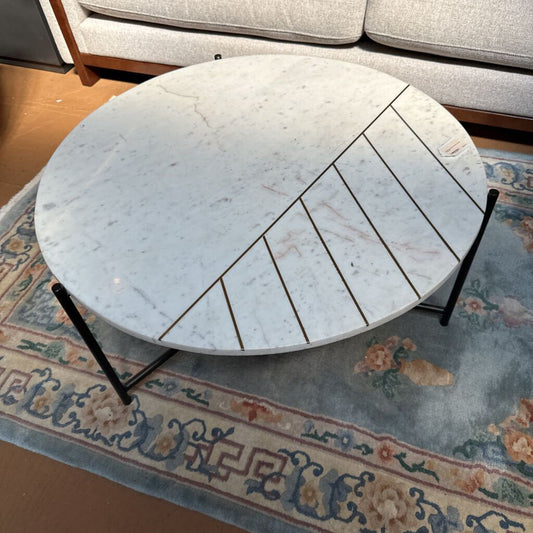 Round marble coffee table with black legs on a patterned rug