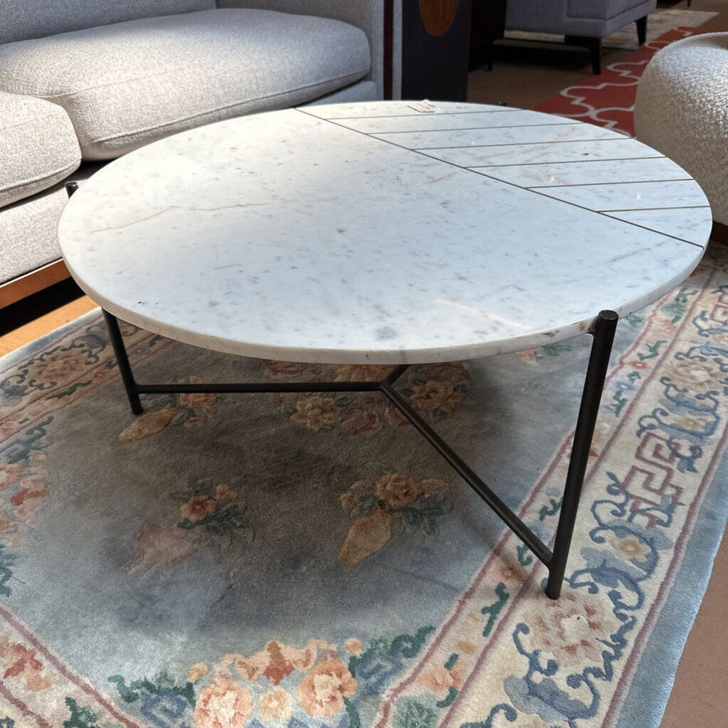 Round marble coffee table with a floral-patterned rug in a living room setting
