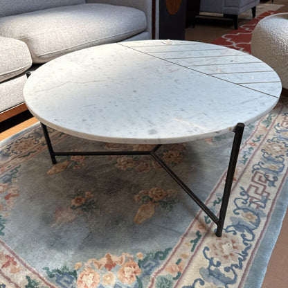Round marble coffee table with a floral-patterned rug in a living room setting