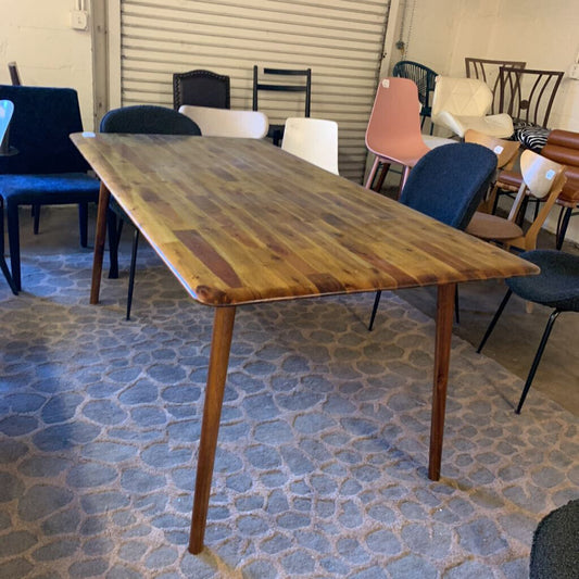 Wooden dining table with chairs in a room with patterned floor and closed blinds.