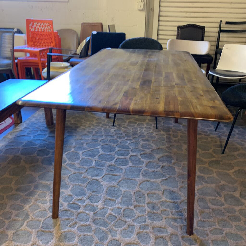 Wooden dining table in a room with chairs and a stone-patterned floor.