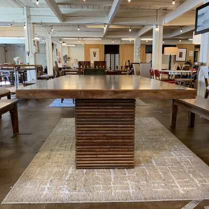 Large wooden dining table in a showroom setting with other furniture and decor.