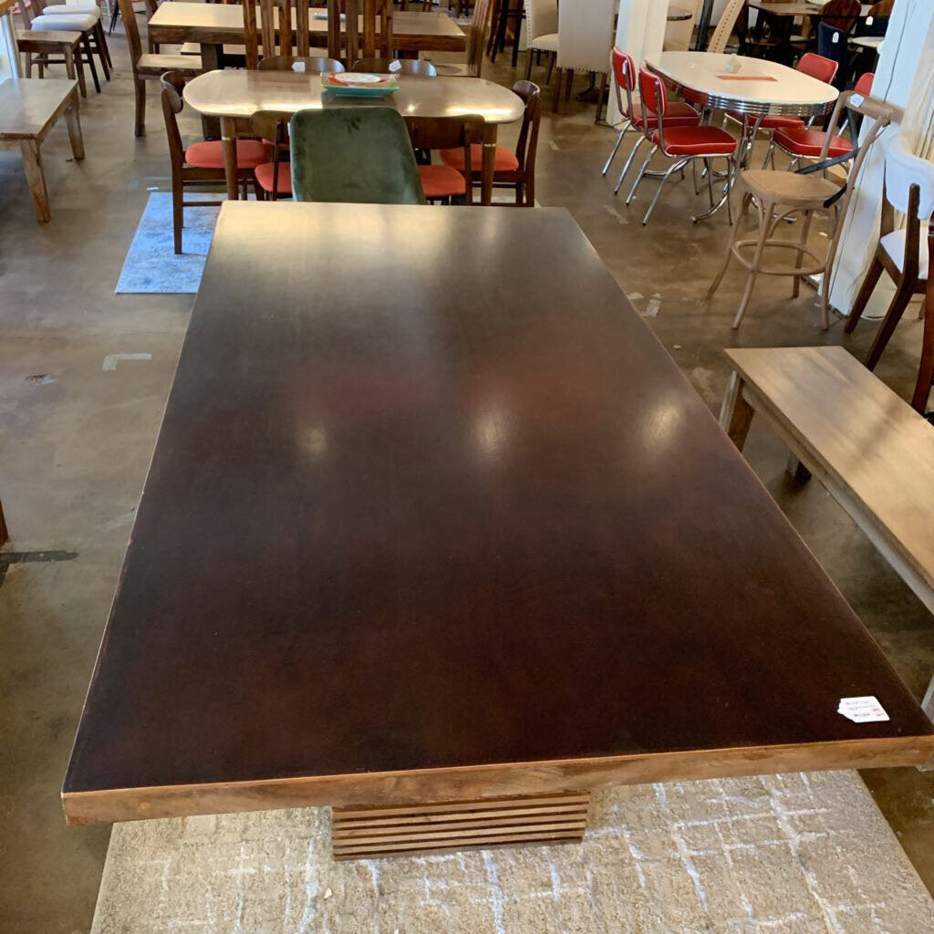 Large wooden table in a room with other tables and chairs