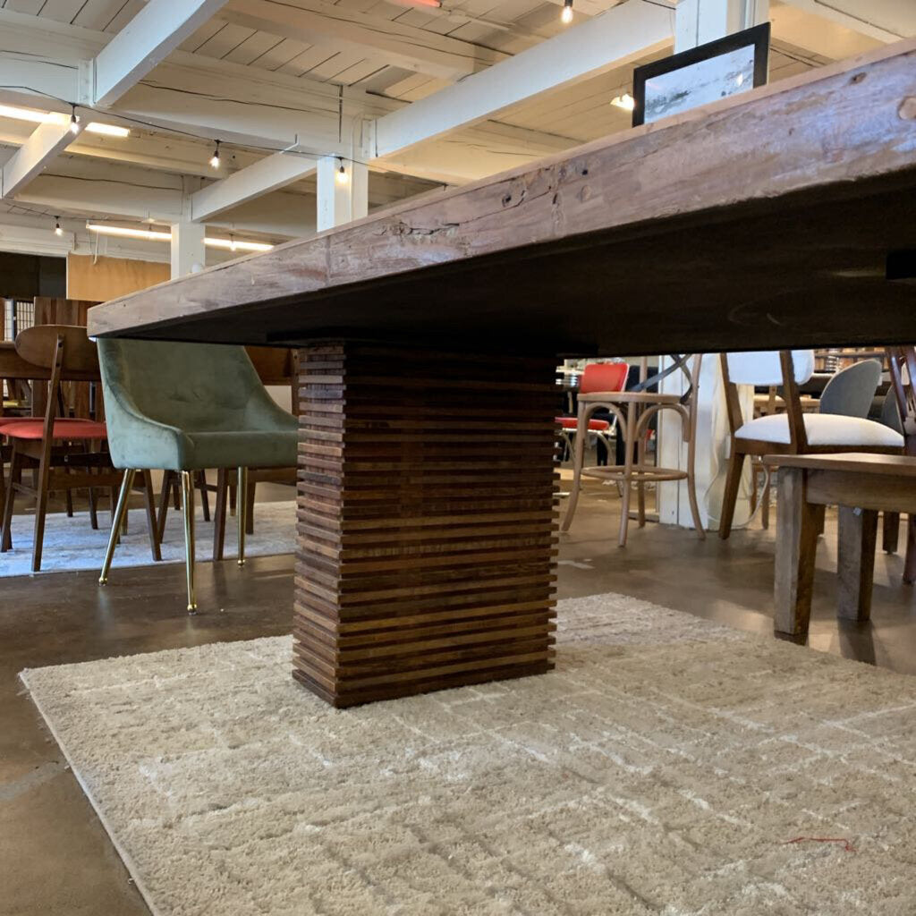 Wooden dining table with a textured base in a modern dining area.
