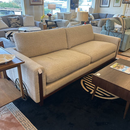 Beige sofa in a furniture store with other couches and decor items.