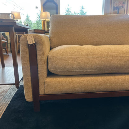 Beige sofa in a room with a dining table and chairs in the background