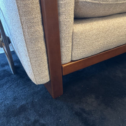 Close-up of a textured chair with wooden armrests on a dark blue carpet.