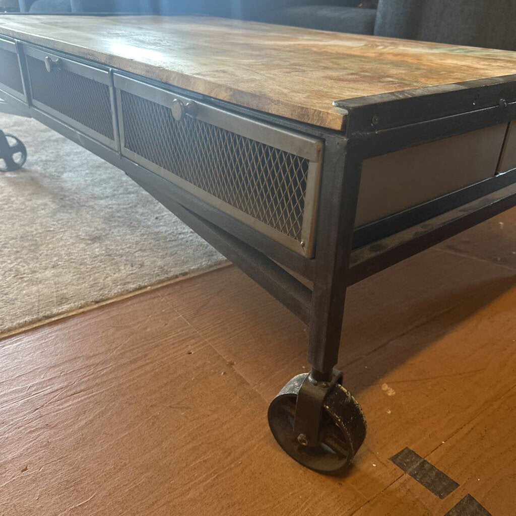 Wooden coffee table with metal frame and wheels on a wooden floor.