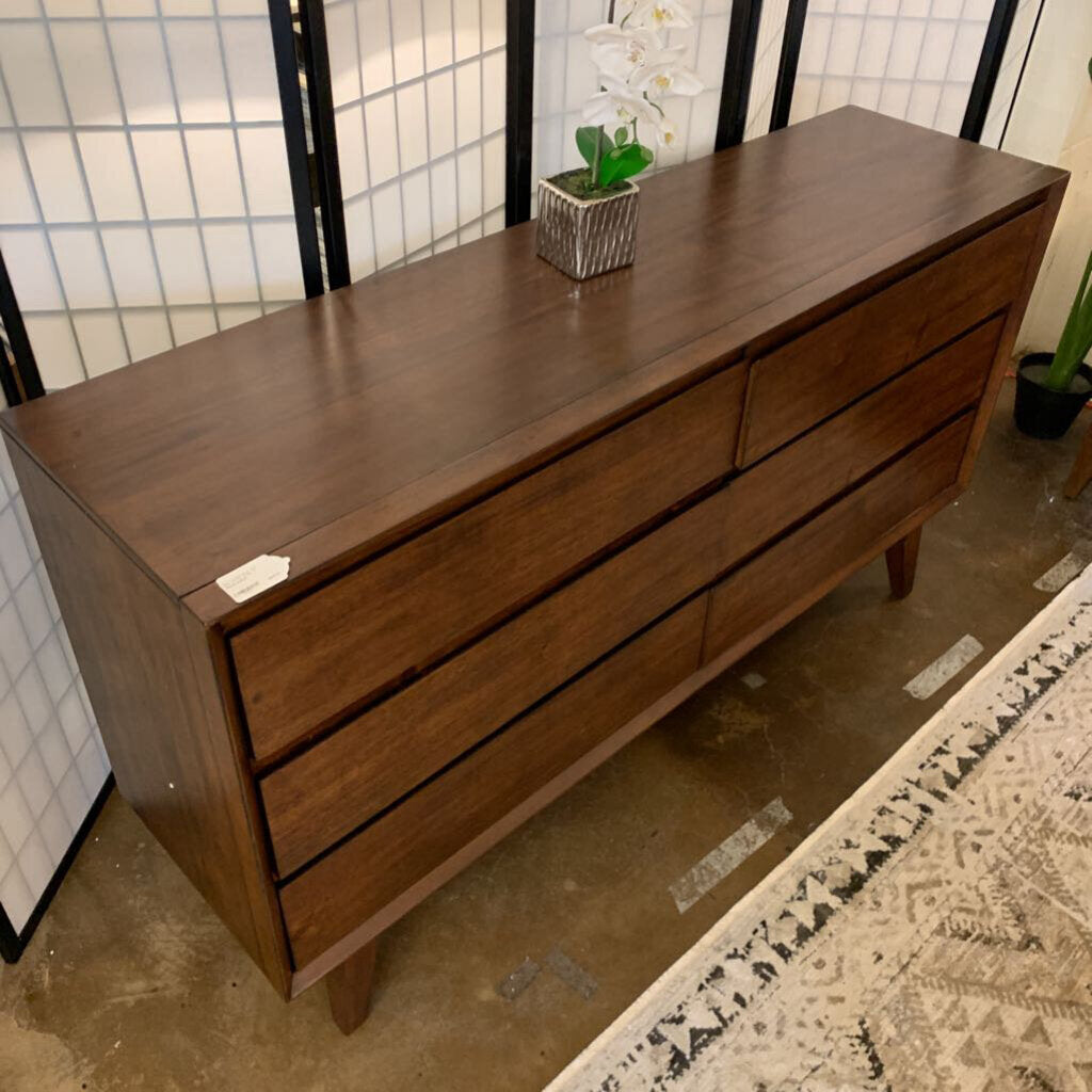 Wooden dresser with multiple drawers in a room setting.