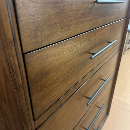 Wooden dresser with metal handles on a wooden floor.