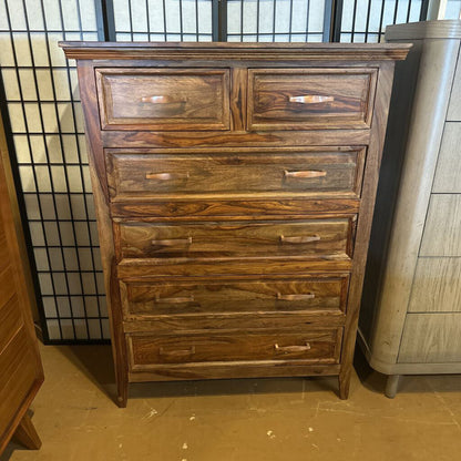 Wooden dresser with multiple drawers against a neutral background