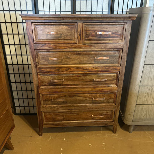 Wooden dresser with multiple drawers against a neutral background