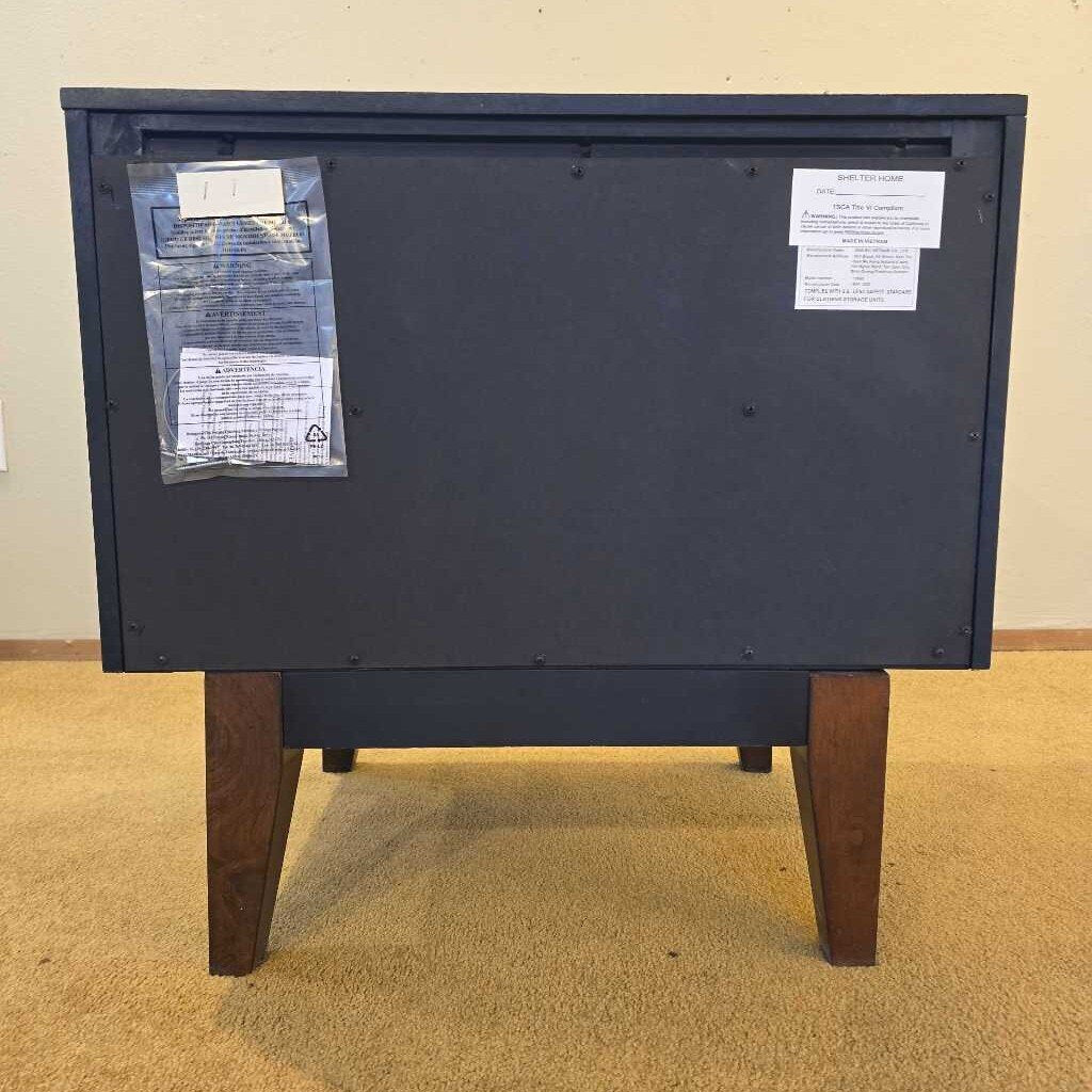 Back view of a black electronic device with labels on a beige carpeted floor.