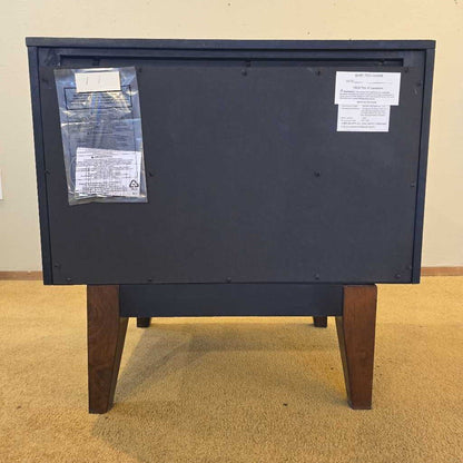 Back view of a black electronic device with labels on a beige carpeted floor.