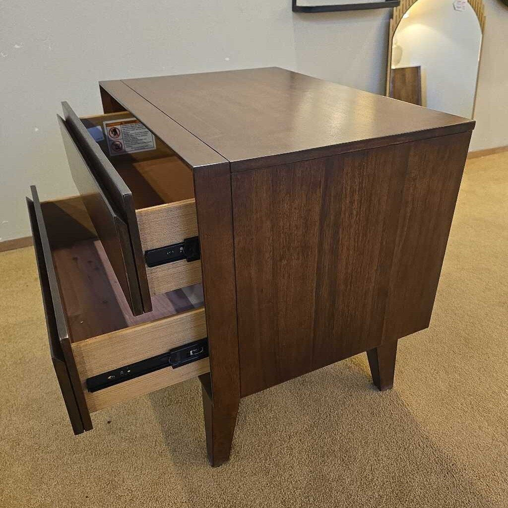 Wooden drawer unit with one drawer open on a carpeted floor.