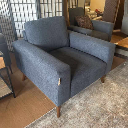 Blue armchair in a room with wooden floor and furniture.
