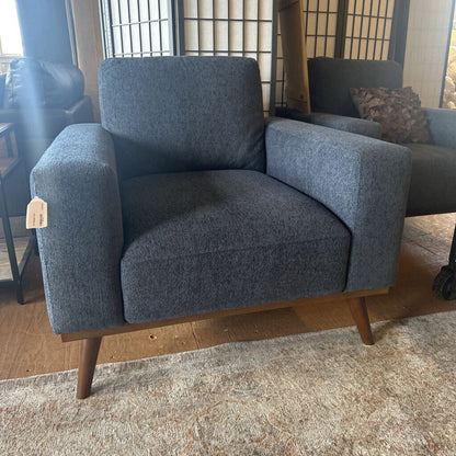 Blue armchair with wooden legs in a room setting