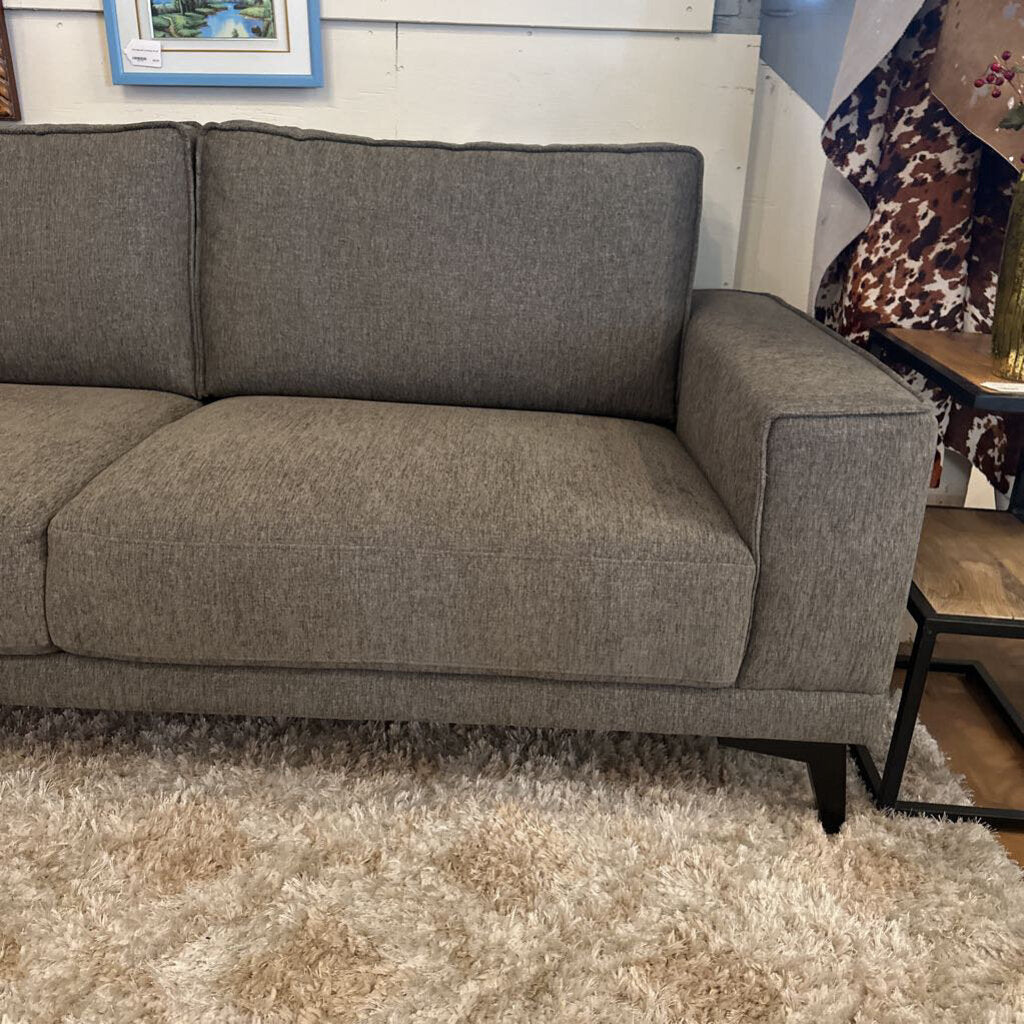 Gray sofa in a room with a wooden floor and a small table.