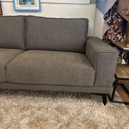 Gray sofa in a room with a wooden floor and a small table.
