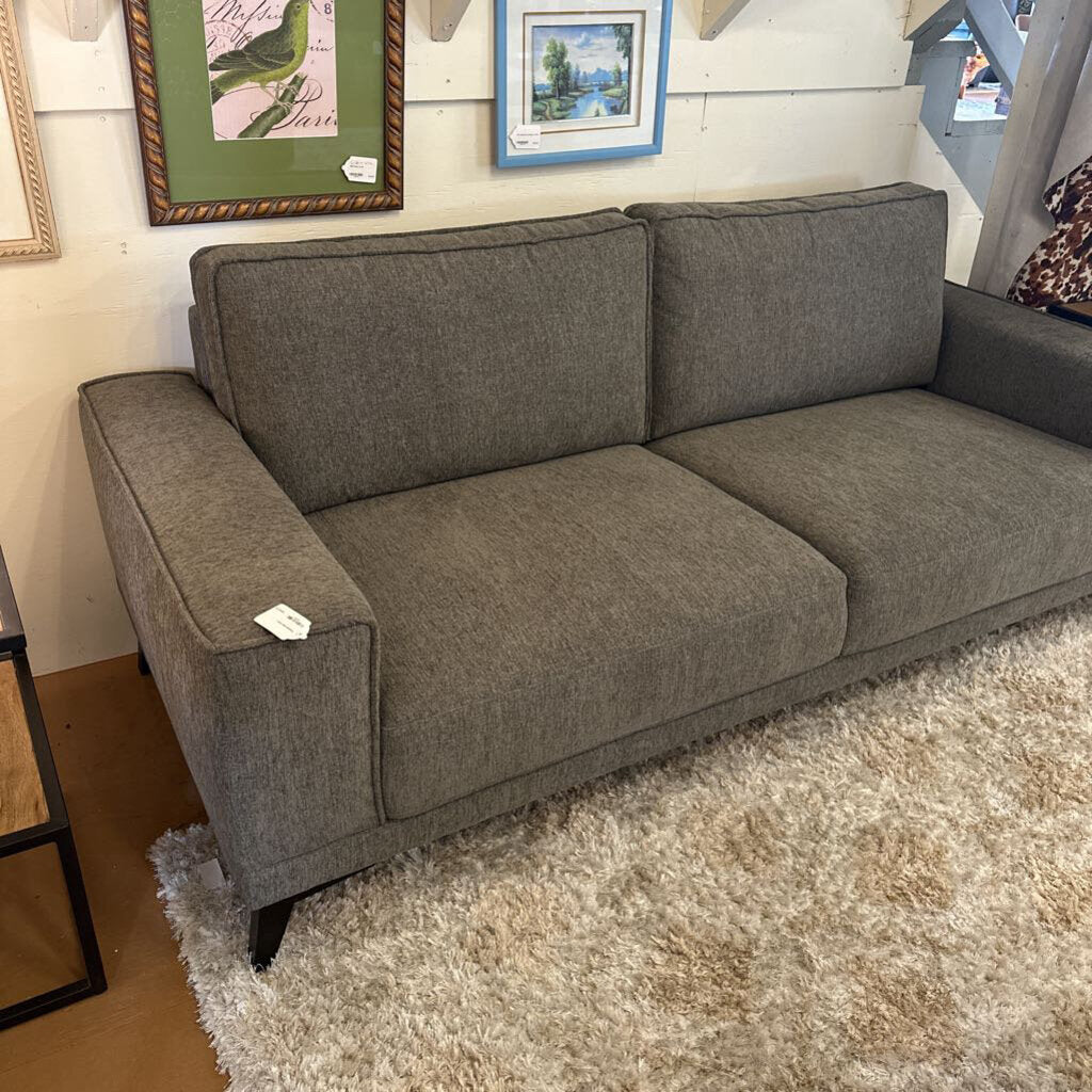 Gray sofa in a room with framed pictures on the wall.