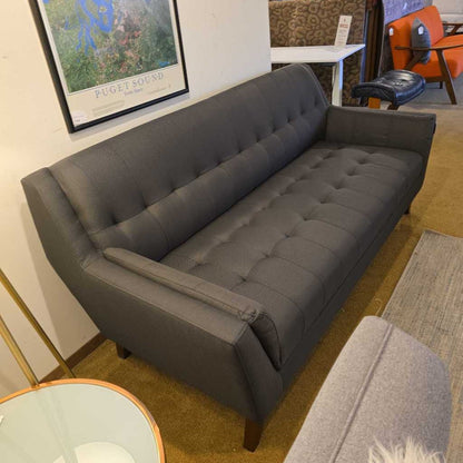 Gray sofa in a room with a map on the wall and chairs in the background