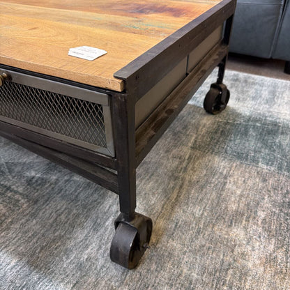 Wooden table with metal frame and wheels on a gray carpet
