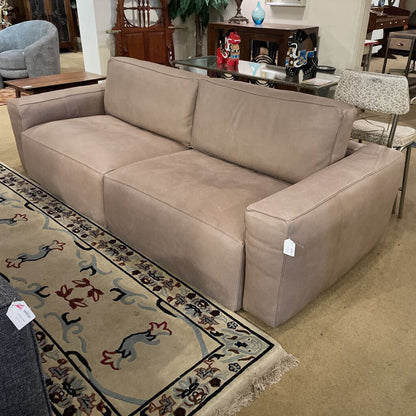 Beige sofa in a room with a patterned rug and furniture.