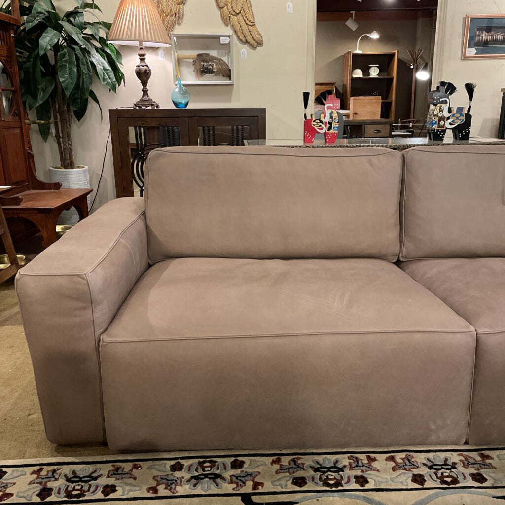 Beige sectional sofa in a living room setting with furniture and decor.