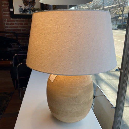 Table lamp with beige base and white shade on a surface