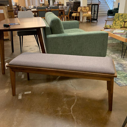 Wooden bench with gray cushion in a furniture store setting