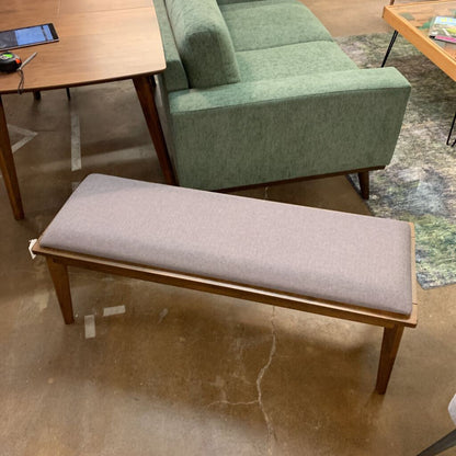 Gray upholstered bench with wooden frame in a room setting