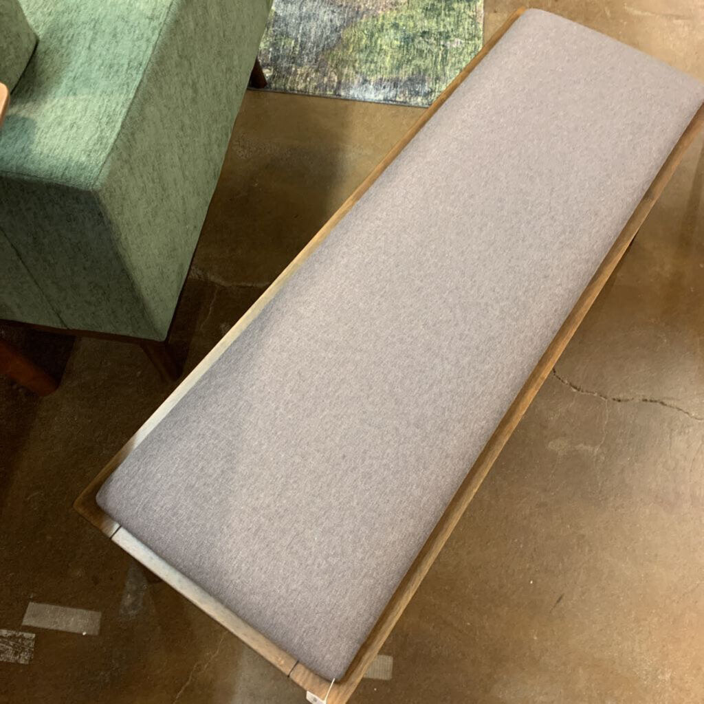 Long gray cushioned bench on a wooden floor
