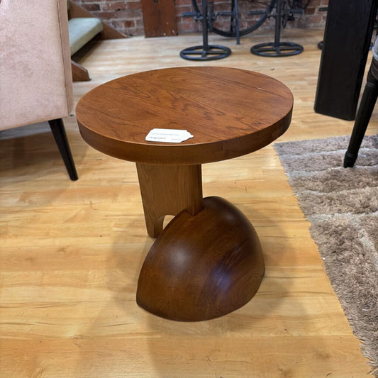 Wooden side table on a wooden floor with a brick wall in the background