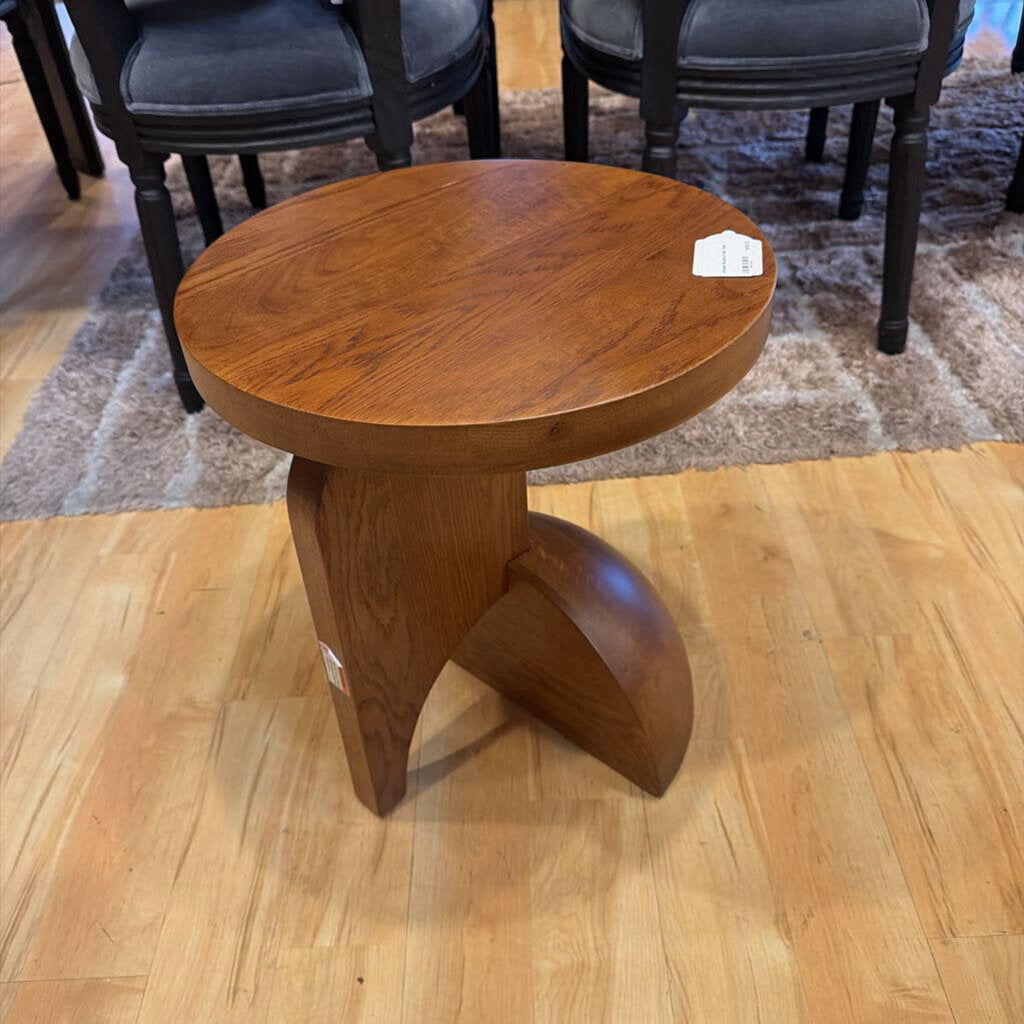 Wooden side table on a wooden floor with chairs in the background