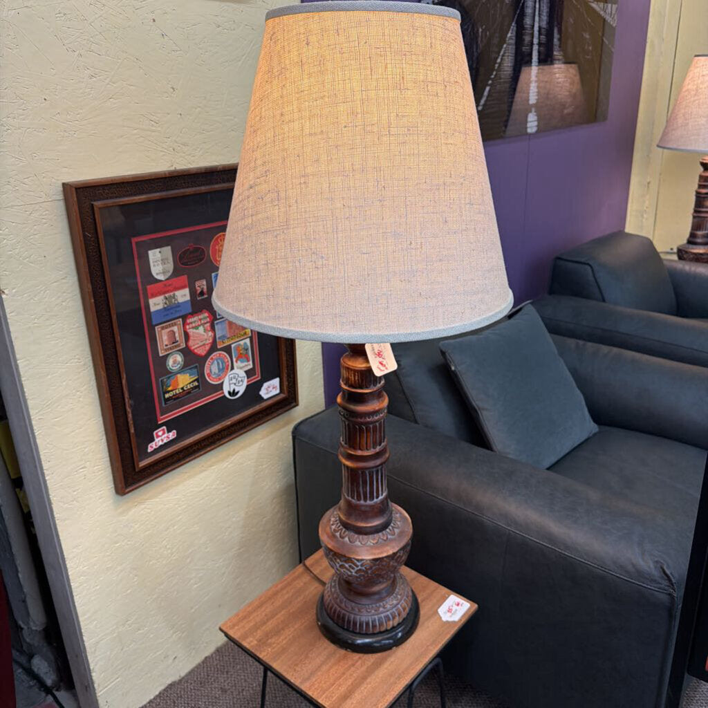 Decorative lamp on a side table next to a gray sofa with a framed picture on the wall.